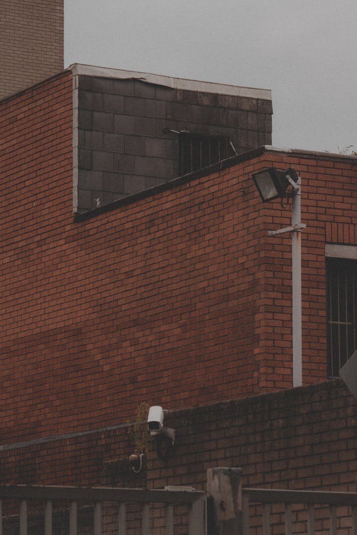 A brick building with surveillance cameras mounted outdoors in an urban setting.